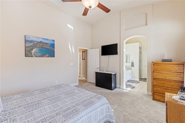 bedroom with ensuite bathroom, high vaulted ceiling, light colored carpet, and ceiling fan