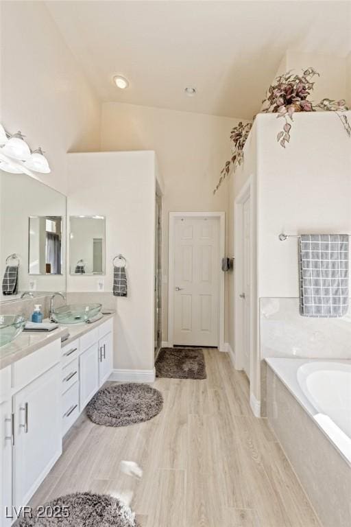 bathroom featuring wood-type flooring, vanity, and a bathing tub