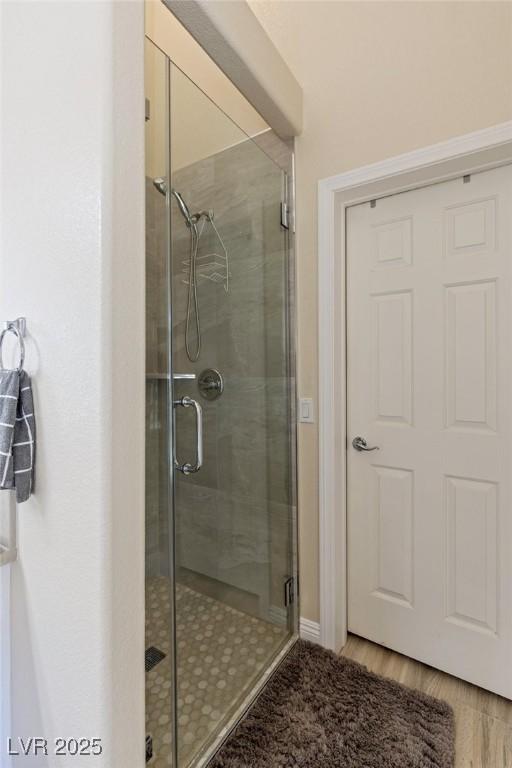 bathroom with wood-type flooring and a shower with shower door