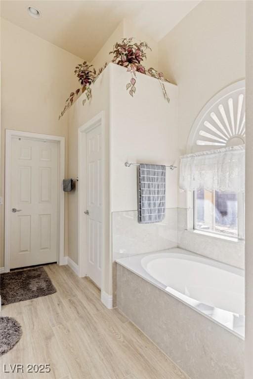 bathroom featuring a bathtub, hardwood / wood-style floors, and lofted ceiling