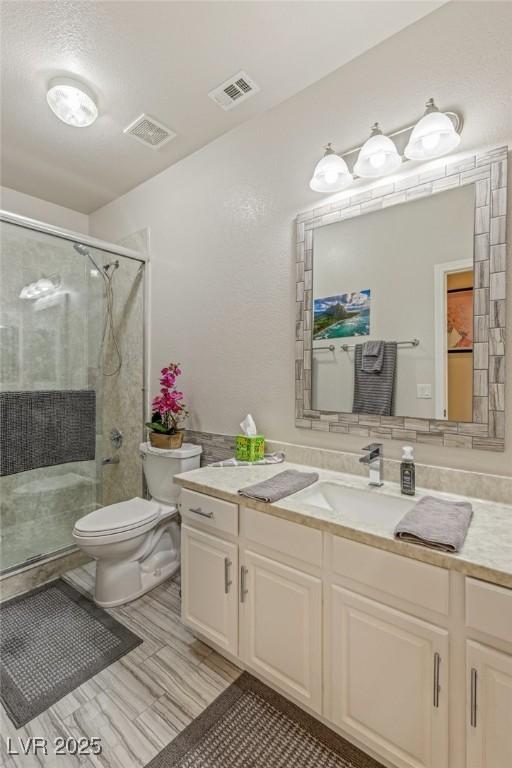 bathroom featuring toilet, an enclosed shower, and vanity