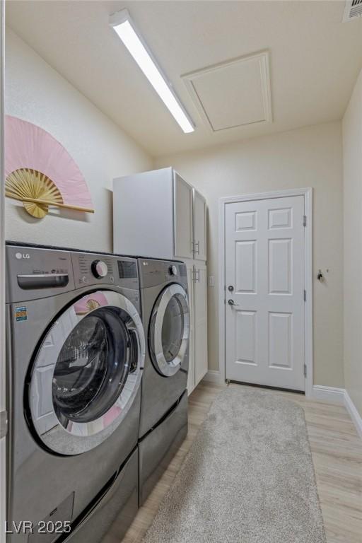 washroom featuring washer and dryer, cabinets, and light hardwood / wood-style floors