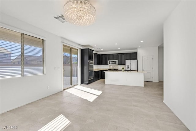 kitchen featuring a notable chandelier, stainless steel appliances, a kitchen island with sink, and light tile patterned floors