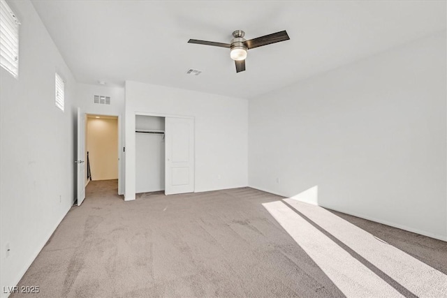 unfurnished bedroom with multiple windows, a closet, ceiling fan, and light colored carpet