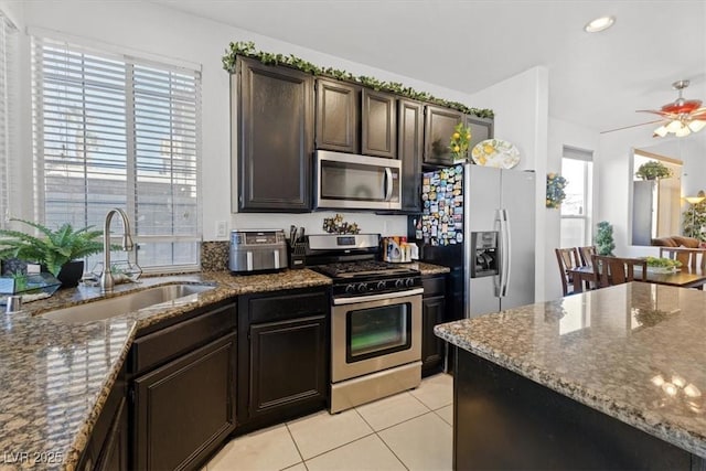 kitchen featuring sink, light tile patterned floors, stone counters, and appliances with stainless steel finishes