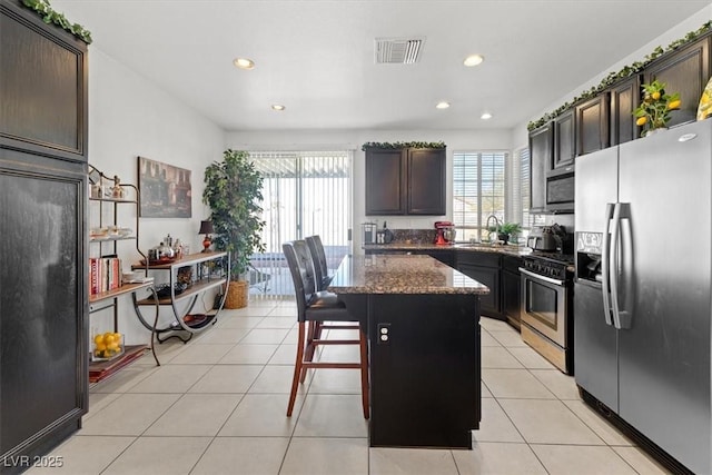 kitchen with appliances with stainless steel finishes, a kitchen breakfast bar, a healthy amount of sunlight, and a kitchen island