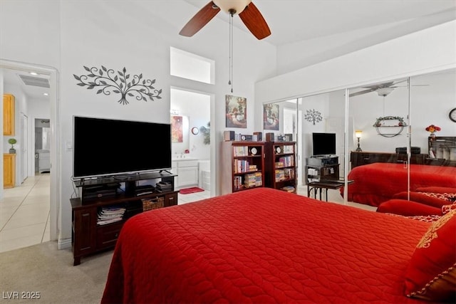 carpeted bedroom with ceiling fan, vaulted ceiling, ensuite bath, and a closet