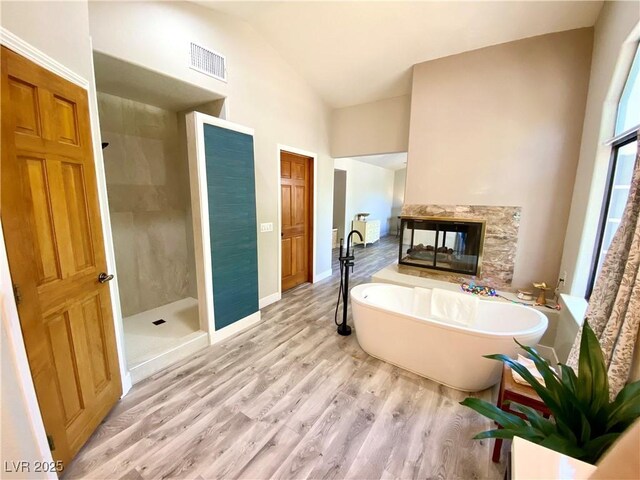 bathroom featuring hardwood / wood-style flooring, vaulted ceiling, and separate shower and tub