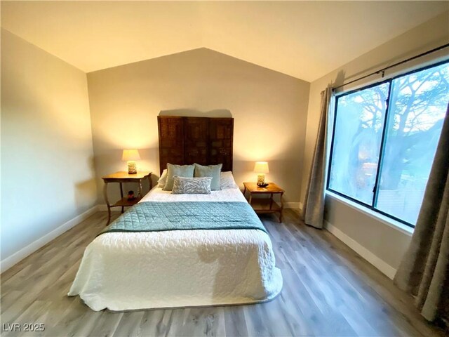 bedroom featuring multiple windows, hardwood / wood-style floors, and lofted ceiling