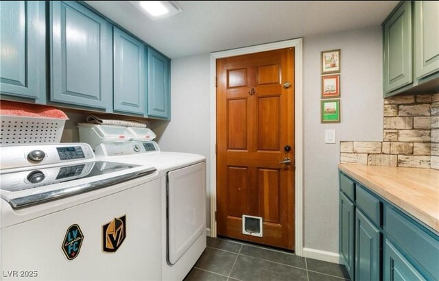 washroom with dark tile patterned floors, washing machine and clothes dryer, and cabinets