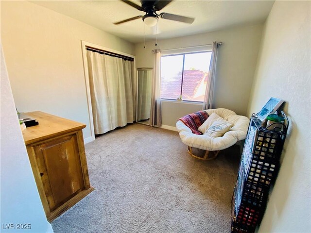 living area featuring light colored carpet and ceiling fan