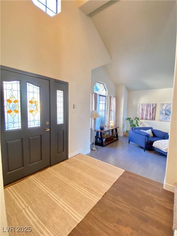 entrance foyer with high vaulted ceiling and hardwood / wood-style floors