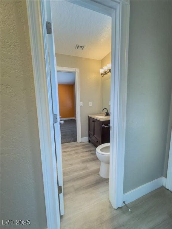 bathroom featuring toilet, wood-type flooring, vanity, and a chandelier