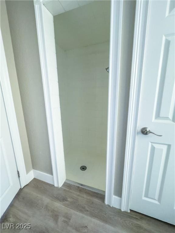 bathroom with a tile shower and hardwood / wood-style floors