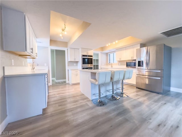 kitchen featuring appliances with stainless steel finishes, white cabinets, a kitchen bar, and a kitchen island