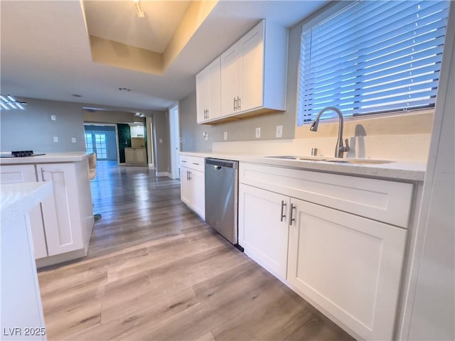 kitchen with sink, white cabinetry, dishwasher, a raised ceiling, and light hardwood / wood-style floors