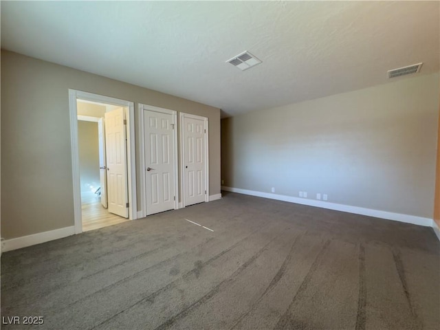 unfurnished bedroom with two closets and carpet flooring