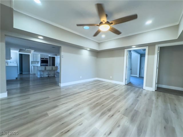 unfurnished living room featuring ceiling fan, wood-type flooring, and sink