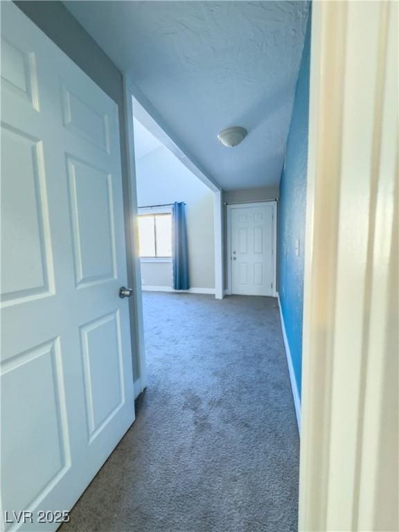 hallway with carpet flooring and a textured ceiling