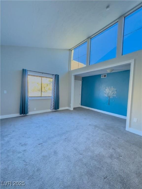 unfurnished living room featuring a towering ceiling and carpet floors