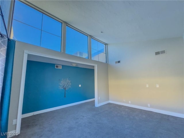 unfurnished living room featuring high vaulted ceiling and dark carpet