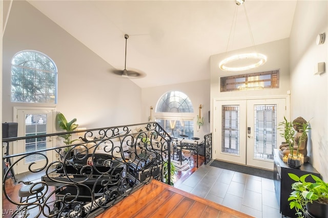 foyer entrance with dark tile patterned flooring, french doors, and high vaulted ceiling