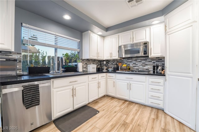 kitchen with stainless steel appliances, white cabinets, tasteful backsplash, and sink