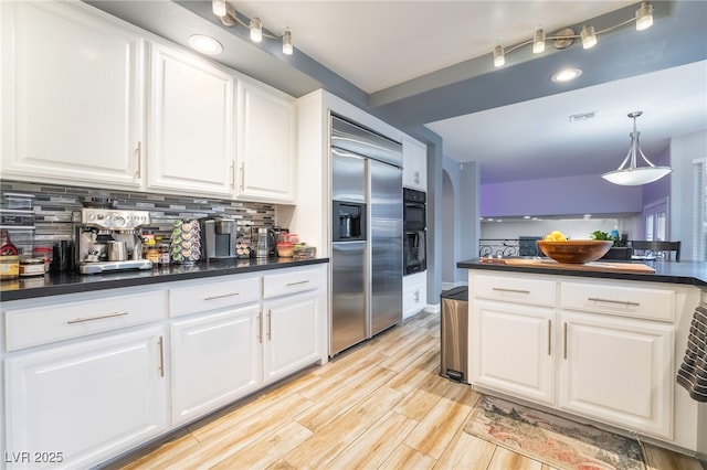 kitchen featuring decorative backsplash, light hardwood / wood-style flooring, white cabinets, double oven, and built in fridge