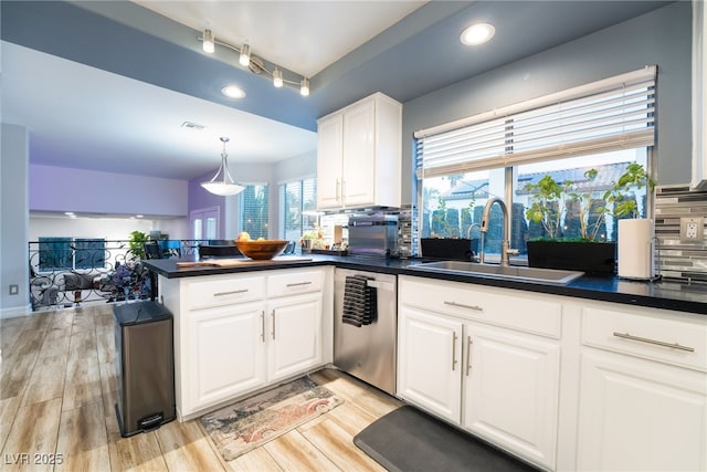 kitchen with tasteful backsplash, dishwasher, kitchen peninsula, sink, and white cabinetry