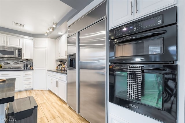 kitchen featuring backsplash, white cabinetry, light wood-type flooring, appliances with stainless steel finishes, and track lighting