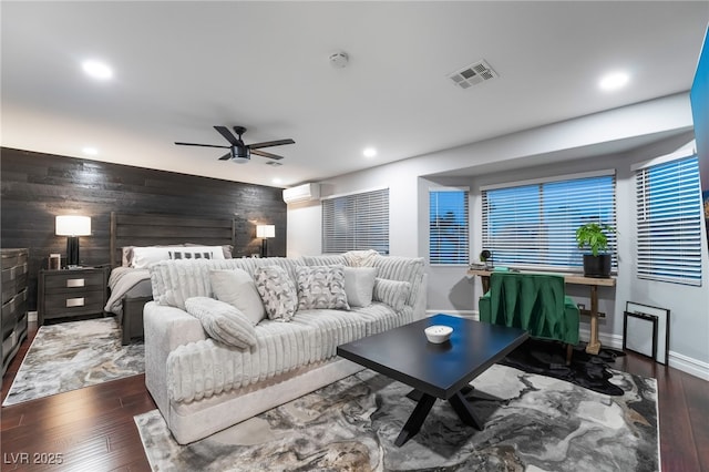 bedroom featuring ceiling fan, dark hardwood / wood-style flooring, a wall mounted AC, and wood walls