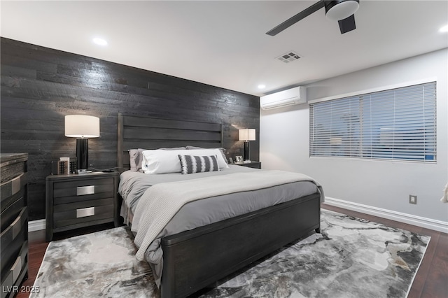 bedroom with ceiling fan, an AC wall unit, dark wood-type flooring, and wood walls