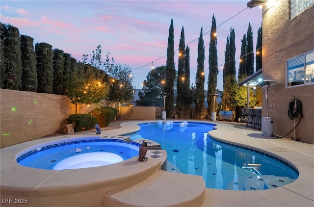 pool at dusk featuring an in ground hot tub, an outdoor bar, and a patio