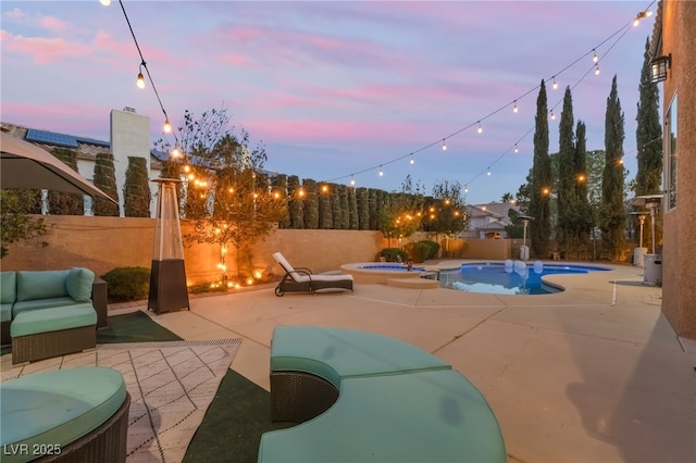 patio terrace at dusk with a swimming pool with hot tub