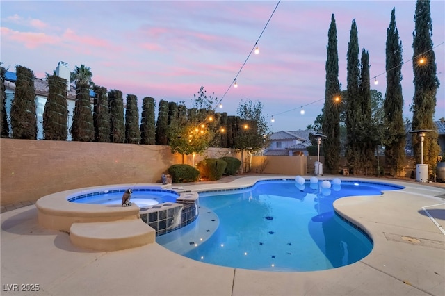 pool at dusk with an in ground hot tub