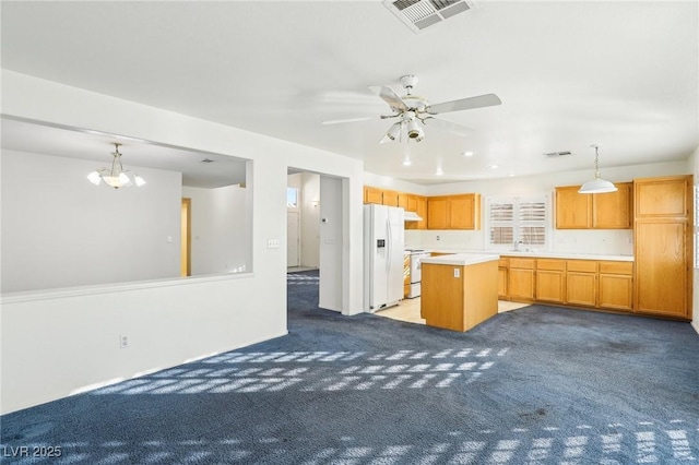 kitchen featuring ceiling fan with notable chandelier, pendant lighting, a kitchen island, white refrigerator with ice dispenser, and light colored carpet