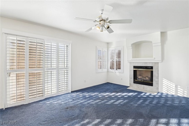 unfurnished living room with ceiling fan, dark colored carpet, and a fireplace