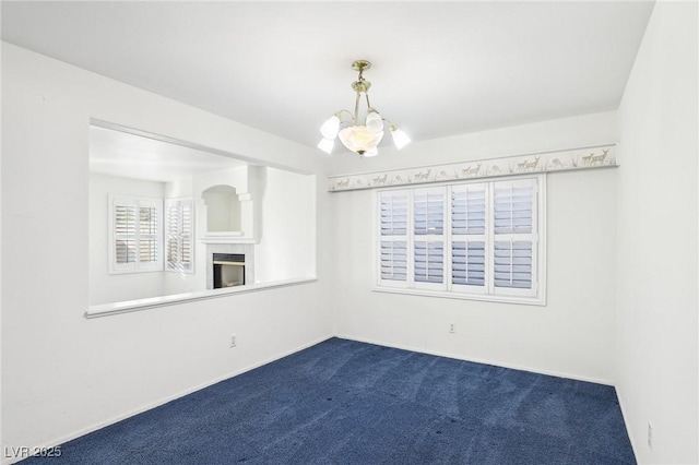 spare room featuring carpet floors and a notable chandelier