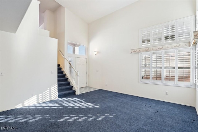 unfurnished living room with carpet floors and a towering ceiling