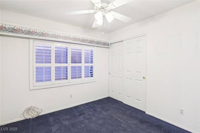 unfurnished bedroom featuring ceiling fan, dark carpet, and a closet