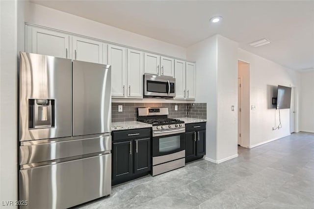 kitchen featuring light stone countertops, white cabinetry, stainless steel appliances, and tasteful backsplash