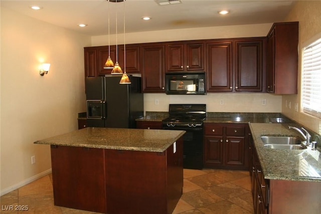 kitchen featuring dark stone countertops, a kitchen island, a sink, black appliances, and decorative light fixtures