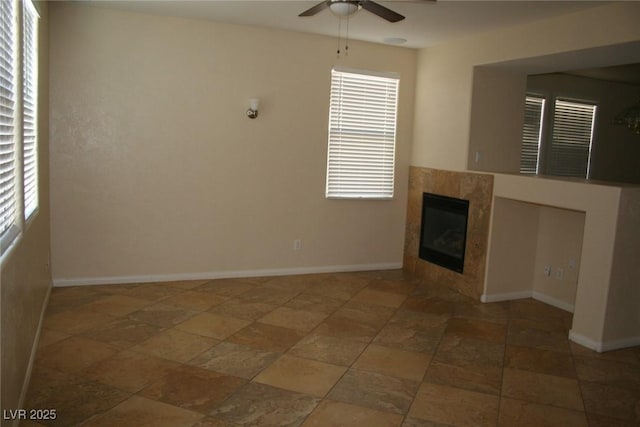 unfurnished living room featuring a fireplace, ceiling fan, and a healthy amount of sunlight