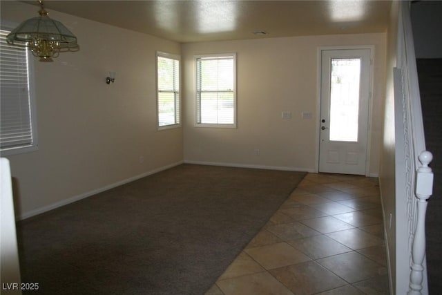 entrance foyer featuring dark tile patterned floors and a notable chandelier