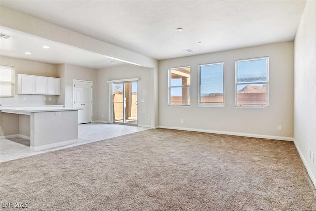 unfurnished living room featuring light carpet and a wealth of natural light