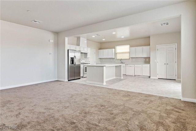 unfurnished living room featuring light colored carpet and sink