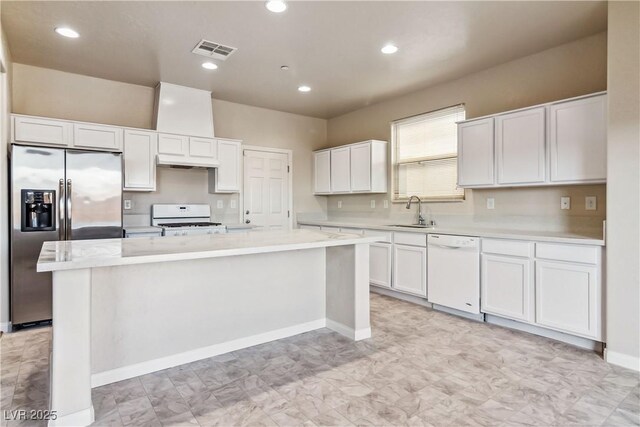 kitchen featuring a kitchen island, sink, white cabinets, and white appliances