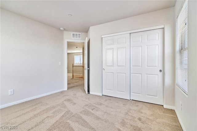 unfurnished bedroom featuring a closet and light carpet