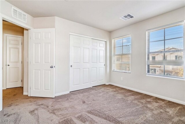 unfurnished bedroom featuring light colored carpet and a closet