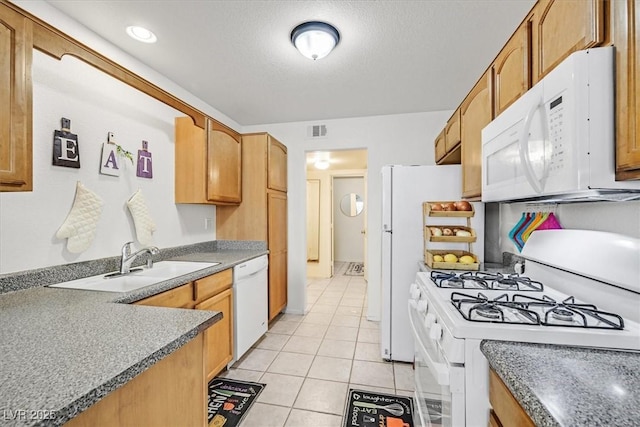 kitchen featuring a textured ceiling, light tile patterned flooring, sink, and white appliances